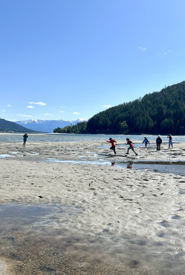 Children running freely and exploring a lakeshore during a forest school day near Nelson BC
