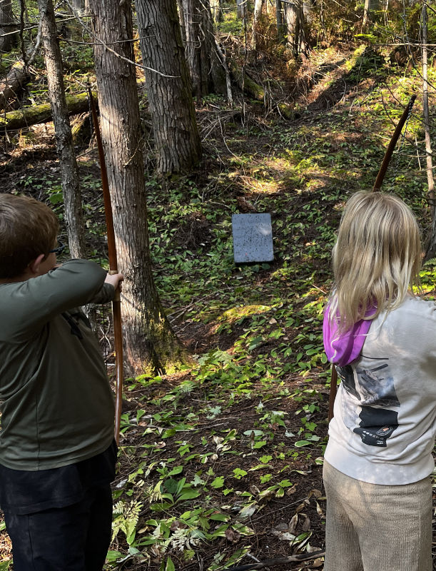 students learning basic archery in the forest at Roots To Sky Forest School near Nelson BC